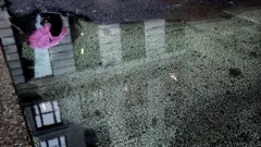 Reflexo no piso de edifício e mulher com guarda-chuva cor-de-rosa