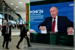 Personas pasan por delante de una pantalla en la que se ve a Putin en el foro económico de San Petersburgo.