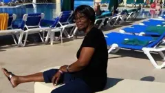 Hyacinth Gage, uma mulher negra sentada numa cadeira à beira de piscina