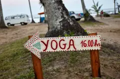 Placa anunciando aula de ioga na praia de Itacaré, na Bahia