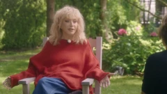 Российская певица Алла Пугачева в саду в кресле в красном свитере и джинсах дает интервью Катерине Гордеевой