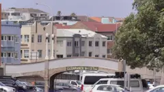 Uma imagem do local do tiroteio que matou 15 pessoas na praia de Bondi, em Sydney, Austrália, mostra uma ponte cinza de 2,7 metros de altura sobre um estacionamento, com prédios ao fundo.