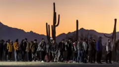 Migrantes em uma fila na fronteira do México com os Estados Unidos.