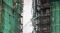 2025年11月27日，香港大埔區宏福苑，一名消防員正用水槍撲滅仍在燃燒的住宅大樓。