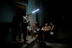 Familia cubana jugando al dominó con una linterna