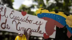 Una persona sostiene un cartel que dice "El Esequibo pertenece a Venezuela" mientras participa en una manifestación en apoyo al referéndum consultivo sobre El Esequibo en Caracas.