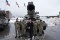 John Healey ao lado de militares em frente a um tanque de guerra