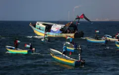 Pequeños barcos de pesca con banderas palestinas en agua del mar.