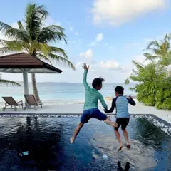 Duas crianças pulando em uma piscina à beira-mar, nas ilhas Maldivas