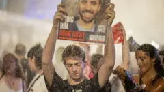 متظاهرون يحملون ملصقات بينما تنشر الشرطة الإسرائيلية خراطيم المياه، في مظاهرة ضد حكومة رئيس الوزراء بنيامين نتنياهو ودعوة للإفراج عن الرهائن في غزة