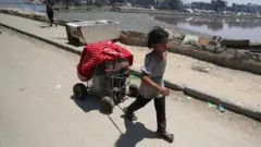 صورة تظهر طفلة فلسطينية تجرّ عربة صغيرة خلال نزوحها عن منزلها في مدينة غزة نهاية يونيو/حزيران.