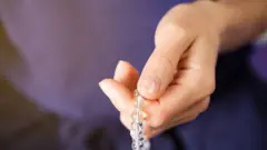 Mão de uma mulher usando uma pulseira de meditação feita de contas de cristal