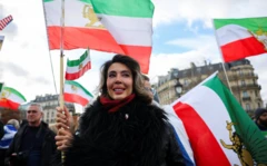 İranlı bir kadın İran bayrağıyla gülerek bir etkinlikte tek başına fotoğraflanmış