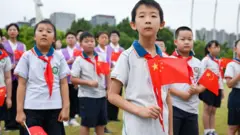 Estudantes com uniformes e carregando bandeiras da China