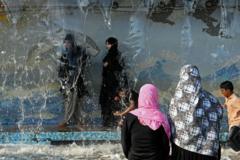 Unas mujeres se refugian del calor en una fuente