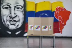 Una mesa de votación y detrás un mural de Chávez