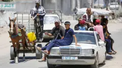 Pessoas em cima de automóveis e outros veículos, fugindo de Deir al-Balah, na Faixa de Gaza