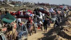 Palestinos deslocados fazem fila para que seus veículos e carroças sejam inspecionados em um posto de controle na estrada para o norte de Gaza