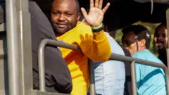 Mfanyakazi wa kigeni akipungia mkono, baada ya kuachiwa huru na moja ya vituo vya utapeli alichokuwa akifanya kazi kwenye mpaka wa Thailand na Myanmar