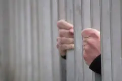 Mãos de homem segurando uma grade