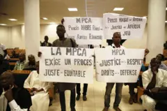 Cuatro manifestantes con pancartas que tienen mensajes con los que exigen justicia y respeto