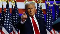 Trump ABD bayrakları önünde işaret parmağıyla birine işaret ediyor