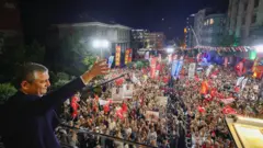 Özel miting alanında bir balkondan kalabalığı selamlıyor. 