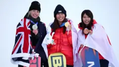 3人が横並びに立ち、首からかけたメダルを左手で胸の前に持ち上げながら笑顔を見せている。それぞれ国旗を肩からかけている