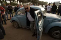 Mujica saindo do fusca azul e uma multidão de pessoas atrás