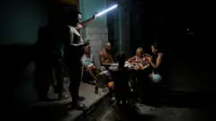 Família cubana jogando dominó à luz de uma lanterna