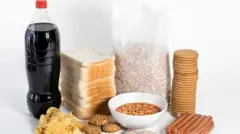 Foto com exemplos de alimentos ultraprocessados: refrigerante, batata chips, pão de forma, macarrão instantâneo, nuggets, cereal matinal, doces e salsichas