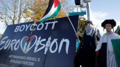 Manifestantes pró-palestinos seguram bandeiras e cartazes em frente aos estúdios da emissora pública irlandesa RTÉ