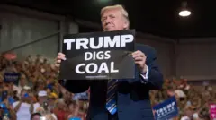 ၂၀၁၇ ခုနှစ်တုန်းက လူထုစုဝေးပွဲတစ်ခုမှာ ထရမ့် ကျောက်မီးသွေး တူးတယ်ဆိုတဲ့ ဆိုင်းဘုတ် တစ်ခုကို ဒေါ်နယ် ထရမ့်က ကိုင်ထားတာဖြစ်ပါတယ် 