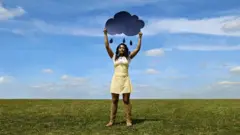 Žena na proplanku drži oblačić u rukama