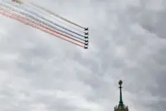 Aviones de combate rusos lanzan humo con los colores de la bandera rusa mientras sobrevuelan el centro de Moscú; en la imagen se aprecia la parte superior de la cúpula de un edificio.