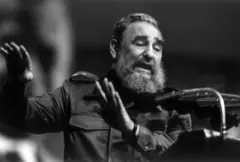 Fidel Castro, vistiendo uniforme militar de faena y con la barba canosa, habla frente a un estrado con micrófonos.