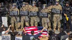 ন্যাশনাল গার্ড সৈন্য এবং পুলিশের মুখোমুখি বিক্ষোভকারীরা