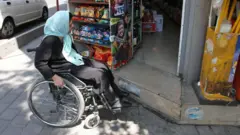 زن دارای معلولیت حرکتی متوقف در برابر یک پله