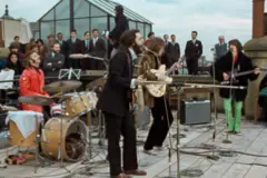 Os Beatles tocam no telhado do número 3 da Savile Row. Paul McCartney está em primeiro plano, debruçado sobre o microfone, enquanto Ringo toca bateria vestindo uma jaqueta de couro vermelha. Atrás deles estão John Lennon e George Harrison, sob o olhar de dezenas de homens de terno.