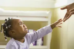 Une fille pleure et tend la main vers un adulte