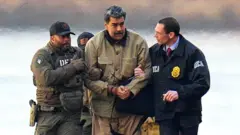  Nicolas Maduro is seen in handcuffs after landing at a Manhattan helipad, escorted by heavily armed Federal agents as they make their way into an armored car en route to a Federal courthouse in Manhattan on January 5, 2026 in New York City.