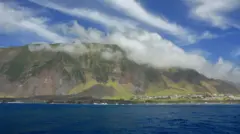 Vista da ilha de Tristão da Cunha em dia de sol e poucas nuvens, com a cidade de Edimburgo dos Sete Mares à direita.