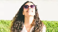 Mulher com óculos escuros tomando sol