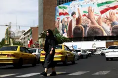 امرأة تمر أمام لوحة إعلانية تحمل صورة المرشد الأعلى الإيراني الراحل، آية الله علي خامنئي، على أحد المباني