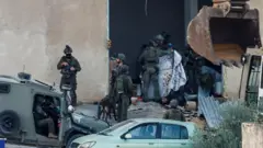 Soldados israelíes cubren con una manta los cuerpos de los palestinos tiroteados durante una redada en Yenín, en la parte de Cisjordania ocupada por Israel.