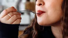 Moça levando garfo à boca