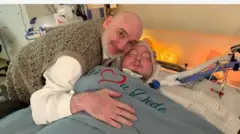 Baba Arẹmọ ree to di mọ ọmọ rẹ lori ibusun.