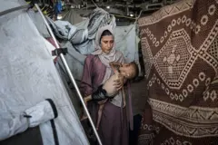 Muhammad Zakariya Ayyoub al-Matouq junto a su madre en una tienda de campaña, en Gaza.