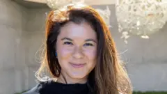 Uma mulher de cabelos longos castanhos sorrindo para a câmera