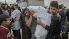 Jóvenes palestinos cargando un saco de alimentos dado por la UNRWA